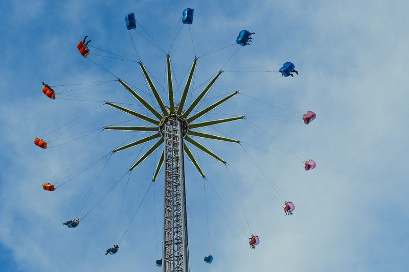 incidental people, funfair, high up, amusement park, park, fairground, theme park, group of people, blue sky, transportation, toy, leisure activities, people
