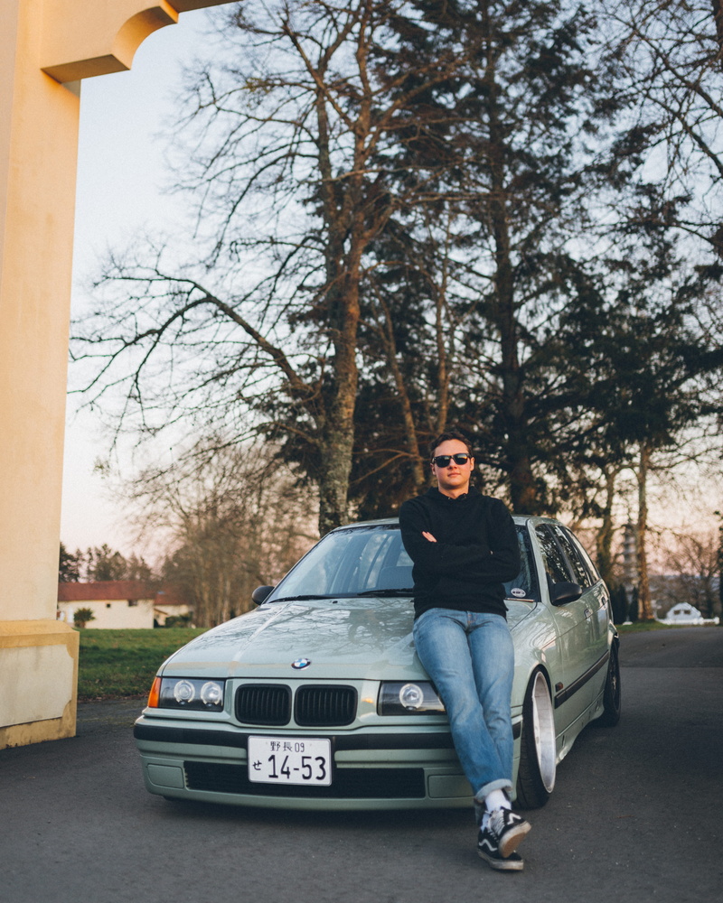 person, clothing, outdoors, full length, 4K, car wheel, human, machine, spoke, bmw, motor vehicle, standing, car, alloy wheel, plant, apparel, transportation