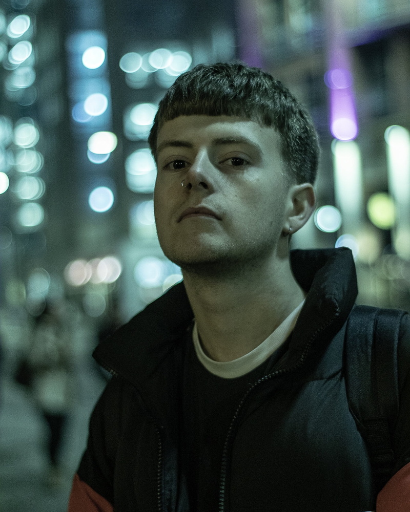 front view, contemplation, modelling, one person, males, canon photography, city lights, looking, city, 0161, real people, portrait, focus on foreground