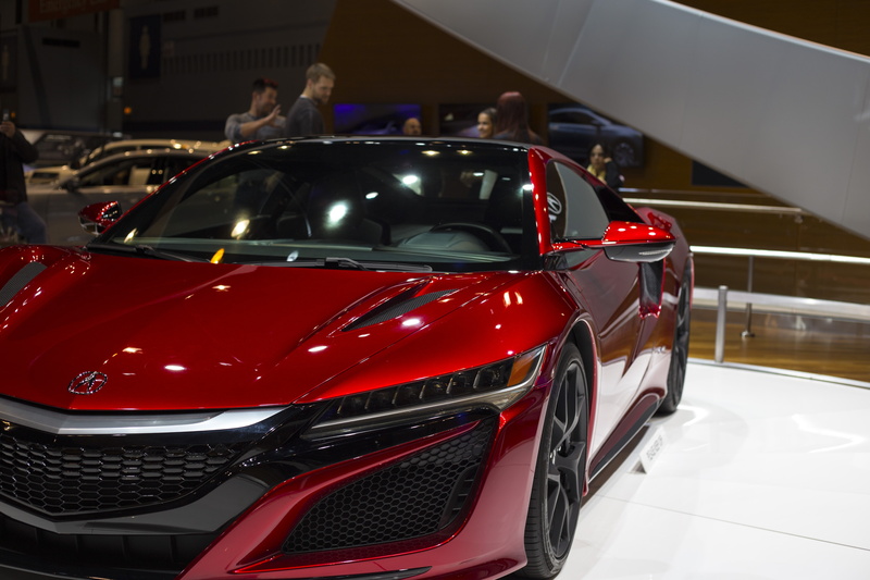 car, incidental people, indoors, day, motor vehicle, red, sports car, mode of transportation, headlight, wealth, shiny, stationary, land vehicle, showroom