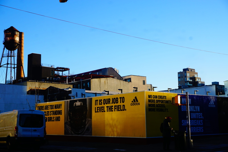 day, advertisement, transportation, road, built structure, nature, mode of transportation, human, metropolis, rail transportation, moving van, sign, urban