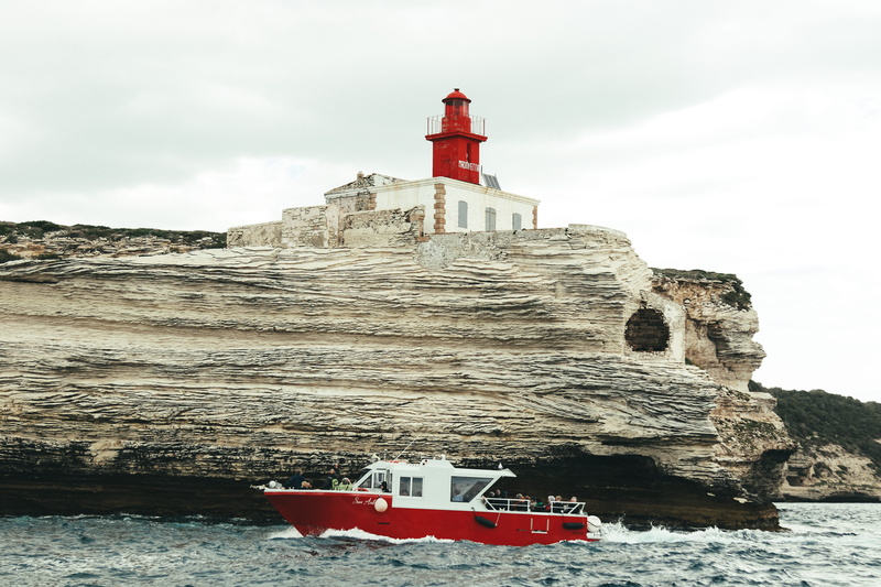 gray, daytime, waterfront, tree, built structure, ocean, building exterior, nature, boat, outdoors, formation, sky, structure, rock, guidance, tower, travel