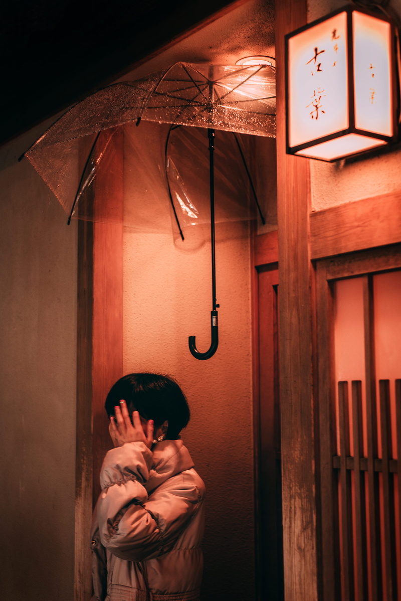 face, entrance, hiding, wood, street, lady, hand covering face, warm clothing, woman, architecture, umbrella, building exterior, stolen, female, waist up