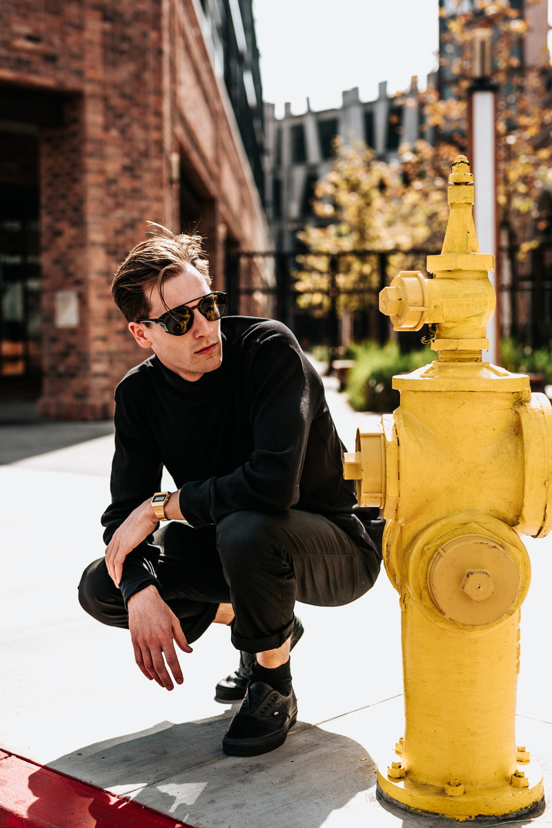 street wear, focus on foreground, keel, sitting, lifestyles, sunglasses, glasses, fashion line, hydrant, front view, posing, shoes, man, full length, young men