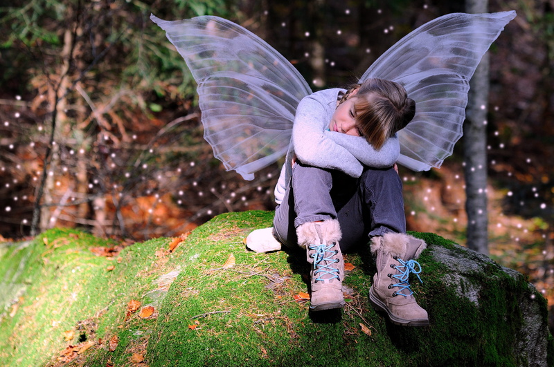 one person, blond hair, focus on foreground, nature, hairstyle, butterfly, photography, hair, sitting, childhood, rock, thoughtful, casual clothing, plant