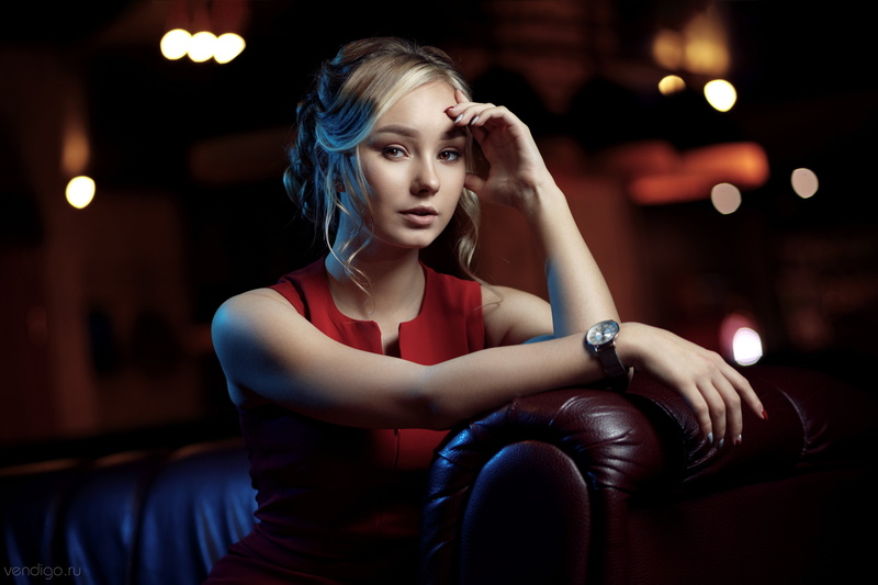 brown eyes, blonde, 5K, red dress, leather couch, Evgeniy Bulatov, portrait, model, hand on face, sitting, women, looking at viewer