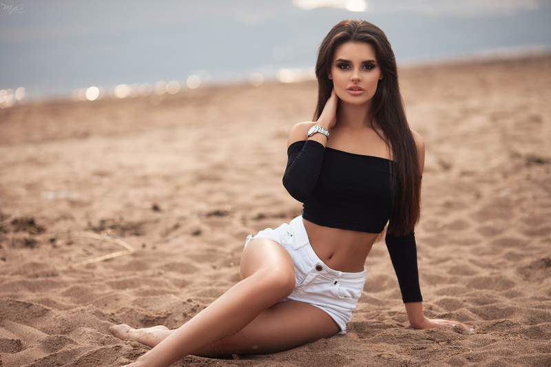 beautiful woman, adult, women outdoors, depth of field, beach, belly, looking at camera, sand, lifestyles, long hair, jean shorts, focus on foreground