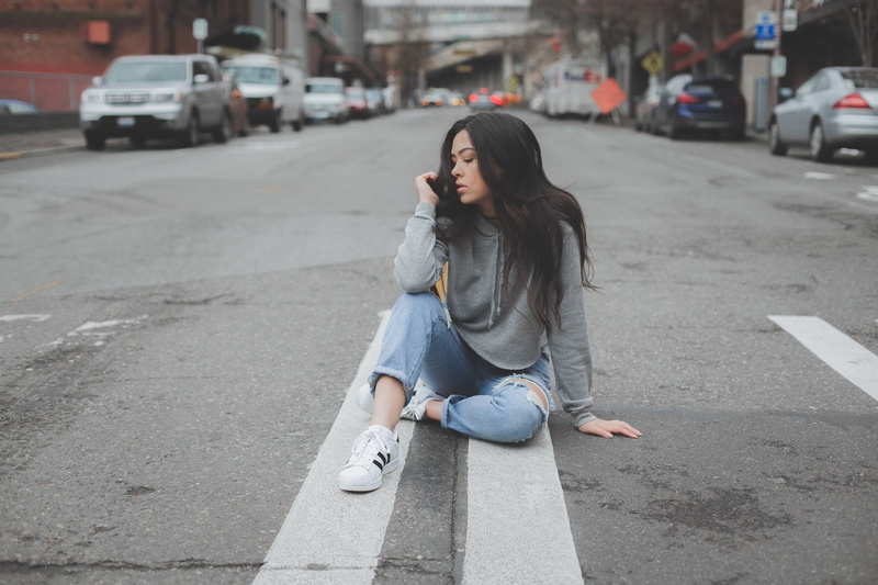 hair, touching hair, city, on the floor, young adult, sitting, road, casual clothing, lifestyles, jeans, full length, beautiful woman, women, long hair