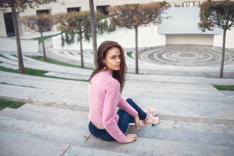 outdoors, leisure activity, young adult, sneakers, sitting, young women, brown hair, built structure, beautiful woman, day, real people, casual clothing