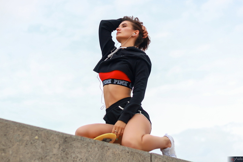 ponytail, pierced navel, belly, brunette, 2K, women, model, women outdoors, short shorts, kneeling, sneakers, holding hair, sky, headphones, sweatshirts