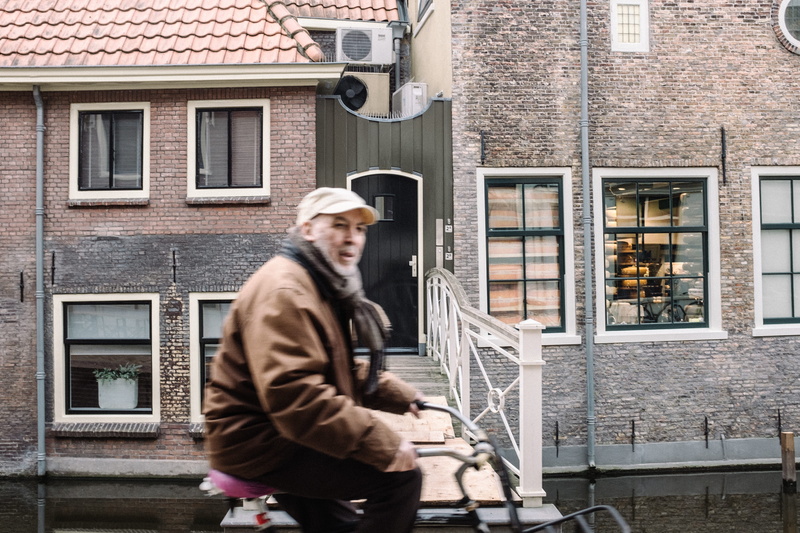 standing, adult, front view, bicycle, gouda, house, architecture, 4K, hat, leather, mid adult, one person, building, man, building exterior, warm clothing