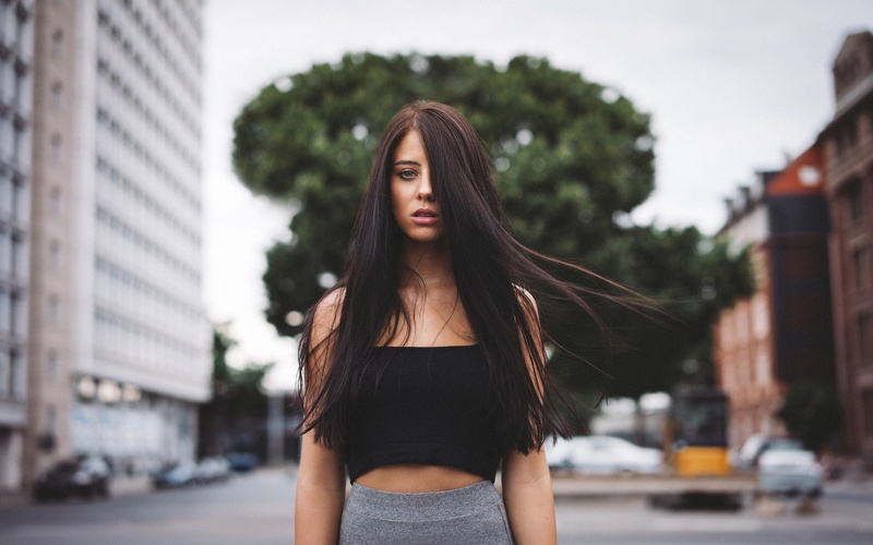 looking at viewer, building, long hair, 1080P, hair in face, model, women, city, trees, urban, Julia Carina, women outdoors, windy, depth of field, black tops