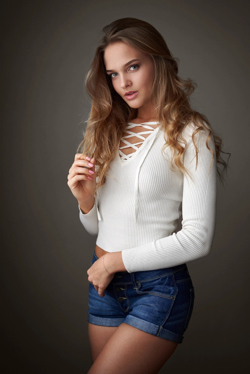 looking at viewer, Milan R, portrait display, women indoors, straight hair, blonde, 1080P, simple background, jean shorts, women