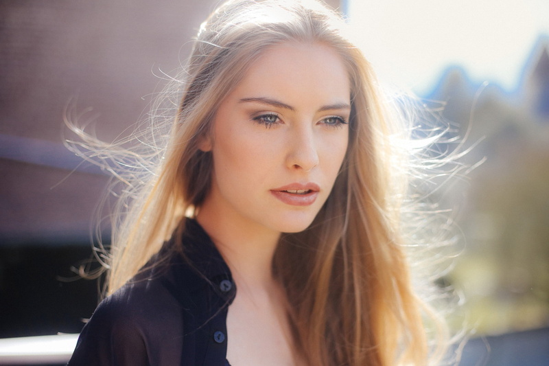 wind, looking at camera, one person, tousled hair, beautiful people, long hair, hairstyle, young adult, beautiful woman, women, blond hair, sunlight, outdoors