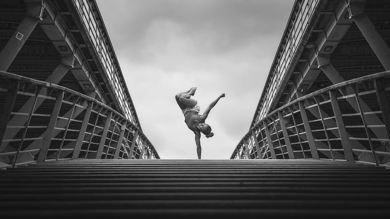real people, cloud - sky, city, skyscraper, sky, full length, monochrome, gymnastics, outdoors, built structure, leisure activity, one person, building exterior