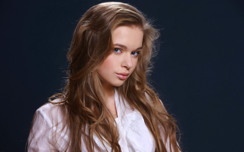 headshot, contemplation, looking at camera, blonde, blue eyes, human hair, hair, black background, indoors, adult, face, young women, long hair, beautiful woman
