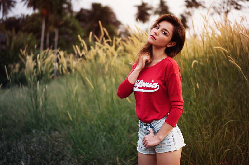 women, 1080P, red clothing, grass, hands in hair, Paul Toma, brunette, looking at viewer, jean shorts