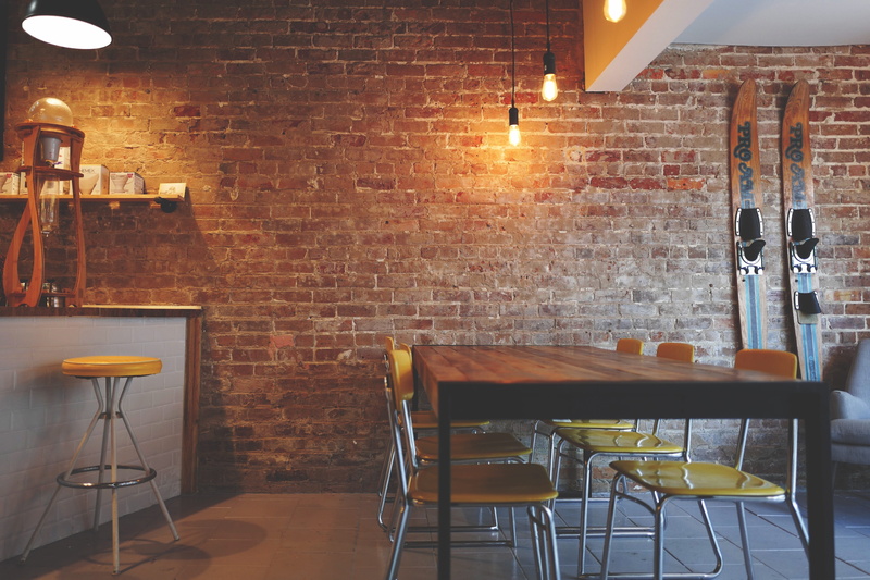 setting, business, yellow, absence, restaurant, wall, lighting equipment, chair, furniture, dining, brick wall, interior design, cafe, table, lights, illuminated