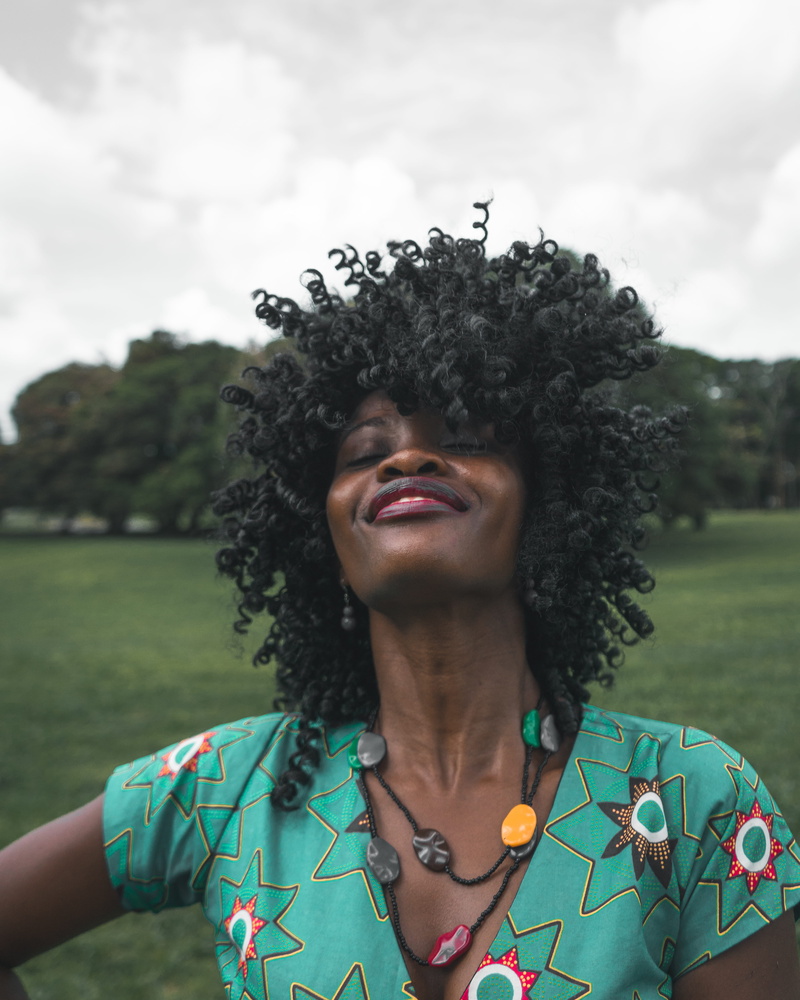 young adult, shirt, casual clothing, outdoors, headshot, posing, tree, energy, one person, tropical, smiling, woman, right, real people, vibe, black woman