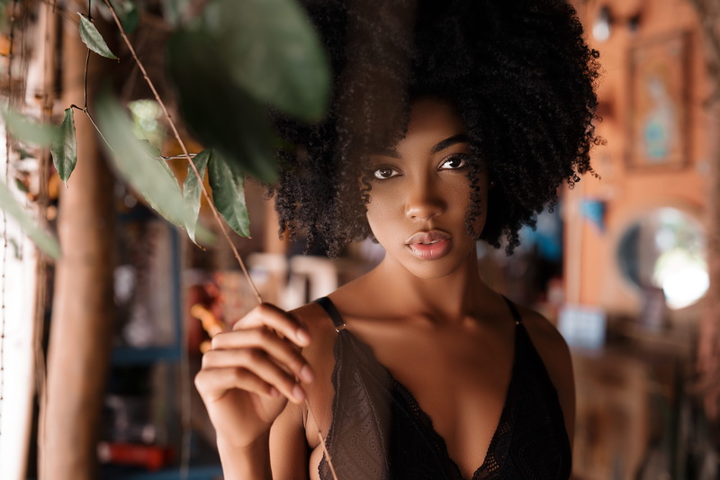 curly, holding, model, fashion, short hair, top, adult, black hair, hairstyle, headshot, strap, one person, woman, focus on foreground, beautiful woman