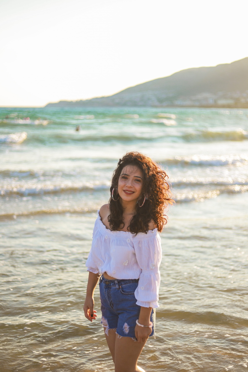 woman, brunette, water, white, three quarter length, land, one person, curly hair, looking at camera, casual clothing, beautiful woman, White Top, smiling