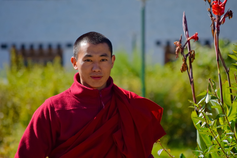 buddhism, one person, travel, blue, looking at camera, vacation, front view, men, plant, outdoors, bhutan, red, buddhist, adventure, god, man, journey