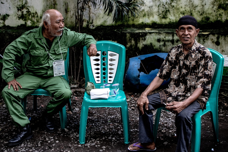 outdoors, leisure activity, indonesian election day, apparel, sit, chairs, talk, real people, man, footwear, talking, human, men, people, seat, shoe, full length