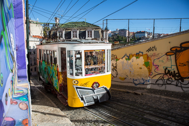 land vehicle, transportation, outdoors, graffiti, sunlight, sun, tram, city, autumn, track, lissabon, mode of transportation, rail transportation, built structure