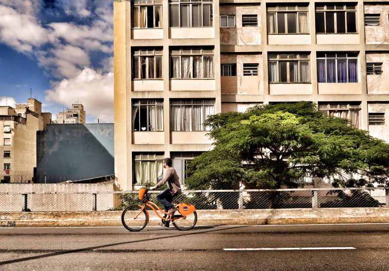 ride, person, outdoors, tree, land vehicle, man, 5K, lifestyles, ｂｉｋｉｎｇ, one person, street, architecture, near, plant, building Exterior, orange, daytime