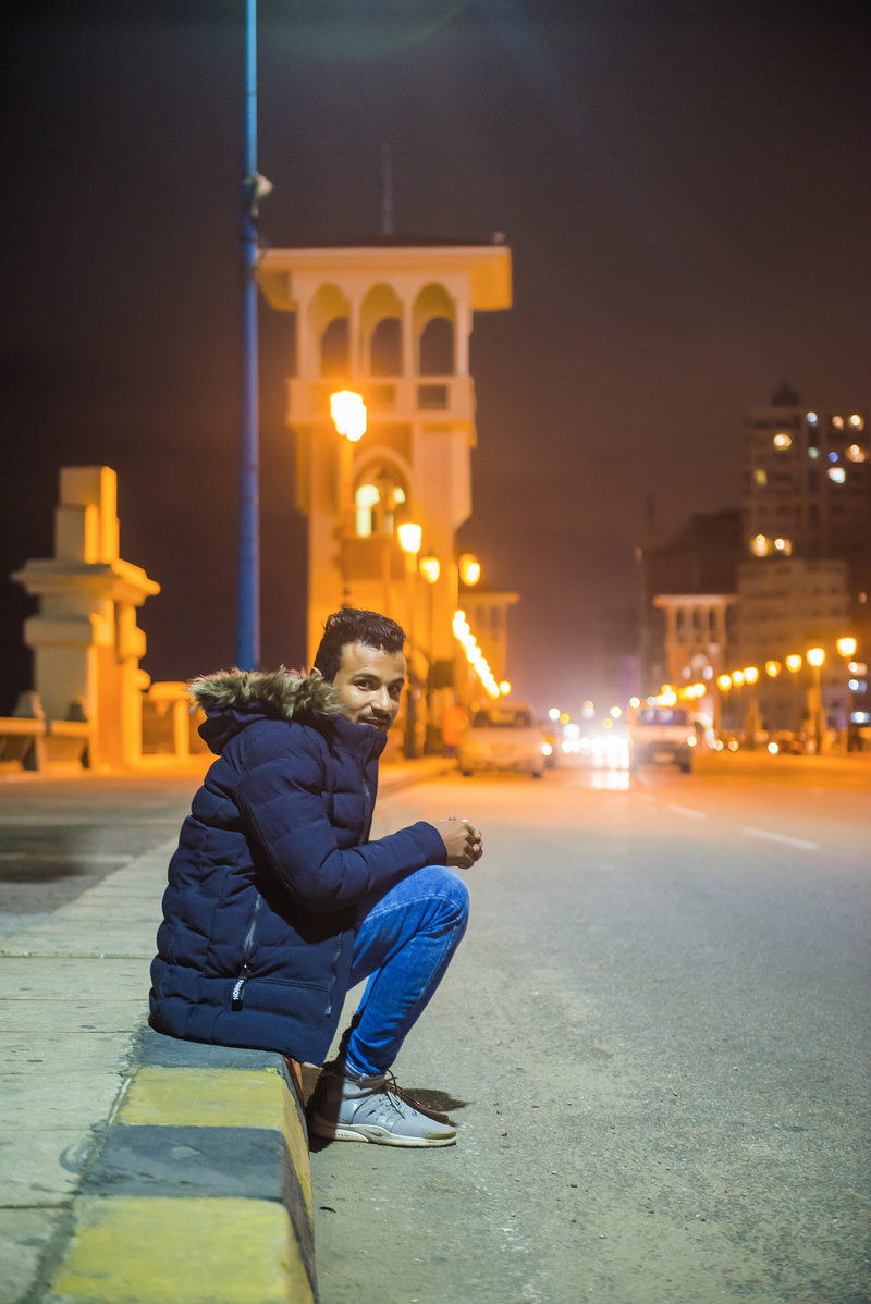 building exterior, leisure activity, zip, near, side view, casual clothing, black, 5K, sitting, buildings, transportation system, road, men, transportation