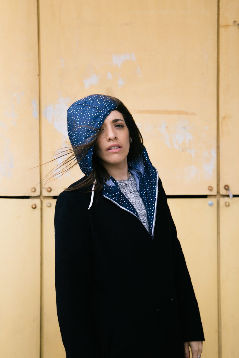 scarf, front view, lifestyles, young adult, contemplation, waist up, brown, looking, beauty, looking away, black, hairstyle, zip, wall - building feature