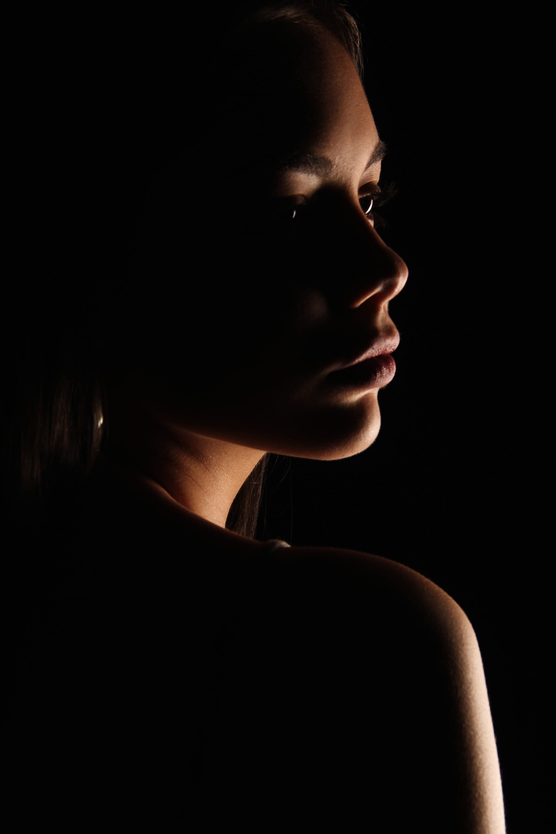 human body part, headshot, girl, adult, colombia, tan, serious, human face, profile, beautiful woman, looking, women, face, shadow, black background, studio shot