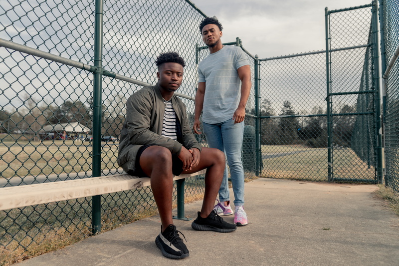 sitting, plywood, apparel, denim, leisure activity, person, two people, bench, full length, prison, adult, togetherness, footwear, shoe, day, park bench