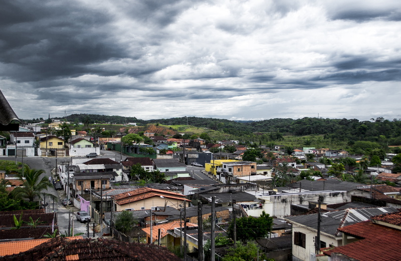 storm, between clouds, town, built structure, tree, building exterior, residential district, favela, nature, cityscape, day, house, plant, roof, outdoors