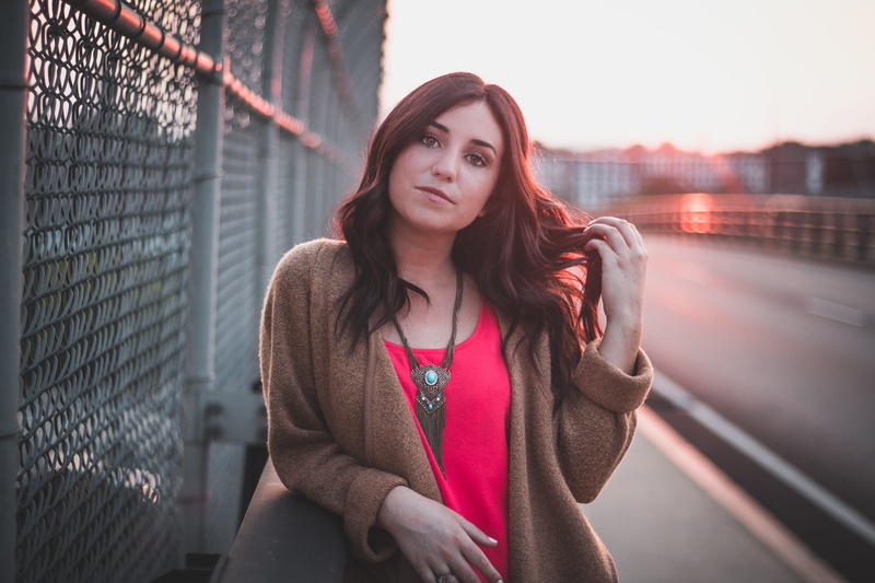 fence, long hair, woman, front view, standing, looking at camera, one person, barrier, holding, adult, clothing, hairstyle, beautiful woman, urban, leaning