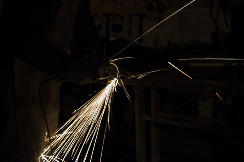 sparks, illuminated, human, fire, indoors, one person, lighting, welding, blacksmith, wood, close-up, iron, sparkle, light, clothing, light trail, motion