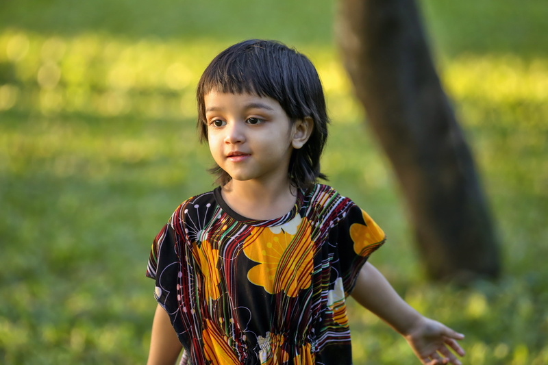 outdoors, casual clothing, front view, outside, natural light, bangs, run, innocence, green, looking at camera, one person, waist up, child, playing, lifestyles