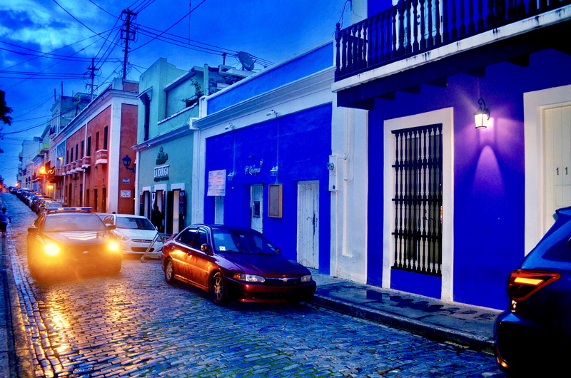 electrical wires, street, car, outdoors, red, passed, city street, near, no people, built structure, headlight, balconies, transportation, travel, mobile