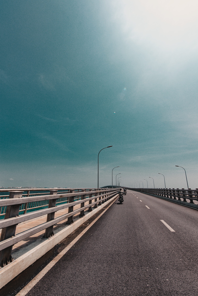 overpass, guard rail, water, banister, human, tarmac, bridge - man made structure, symbol, crash barrier, building, pier, diminishing perspective, vanishing point