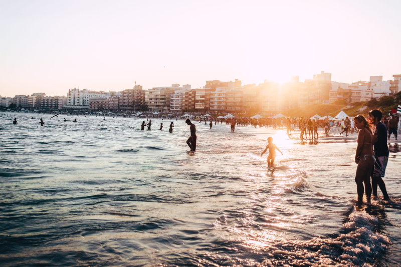 people, ocean water, holiday, outdoors, day, bright, sun, built structure, sunlight, sky, real people, near, crowd, bathing, praium, clear sky, people on beach