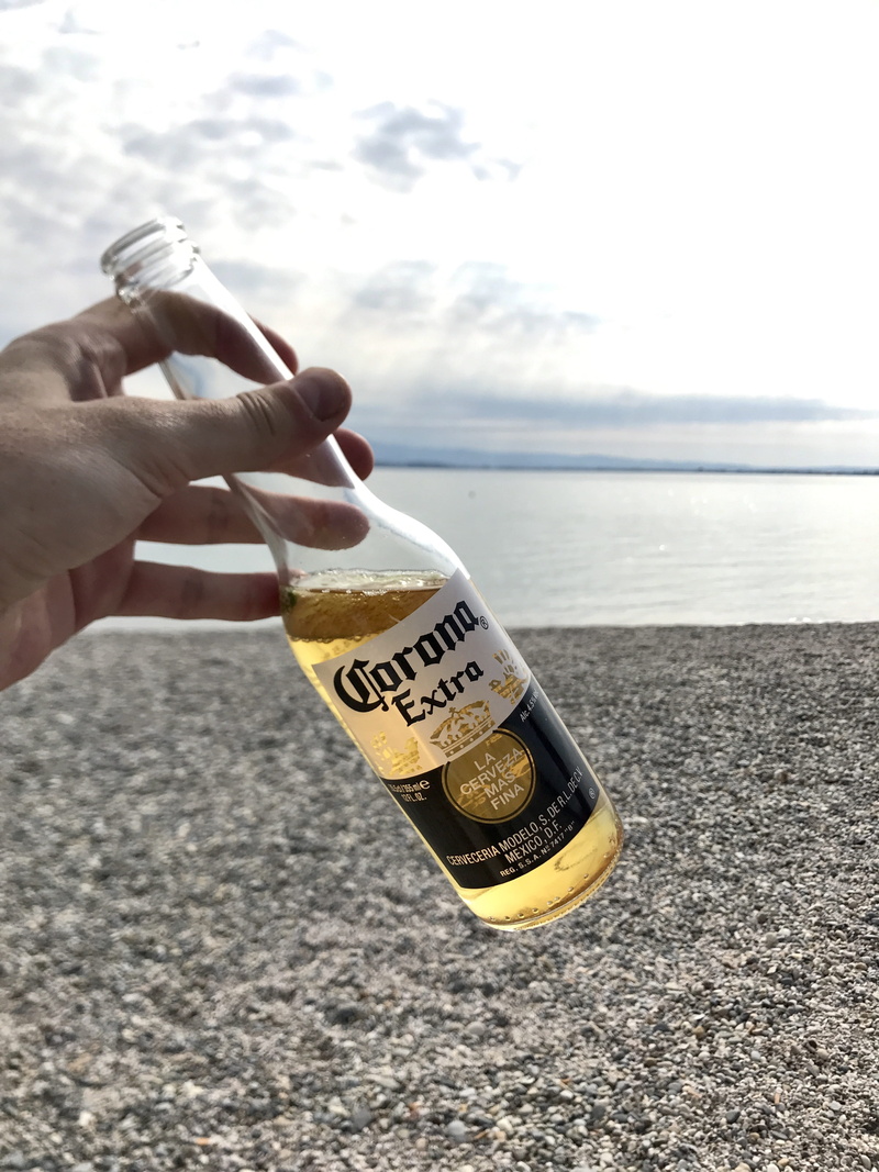 Corona Extra, body part, wine bottle, text, clouds, food and drink, bottle, unrecognizable person, finger, day, human body part, Beer, real people, human hand