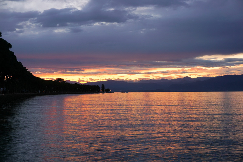 orange color, leisure, cloud - sky, sunset, vacations, reflection, green, romantic, lake, tranquility, garda, beauty in nature, idyllic, bank, lago di garda