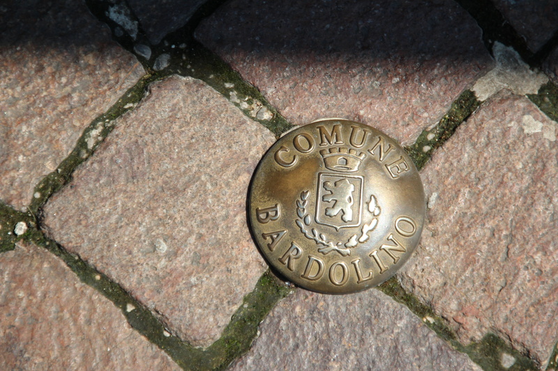 shape, text, carving - craft product, paving stone, finance, close-up, art and craft, full frame, representation, circle, communication, comune bardolino