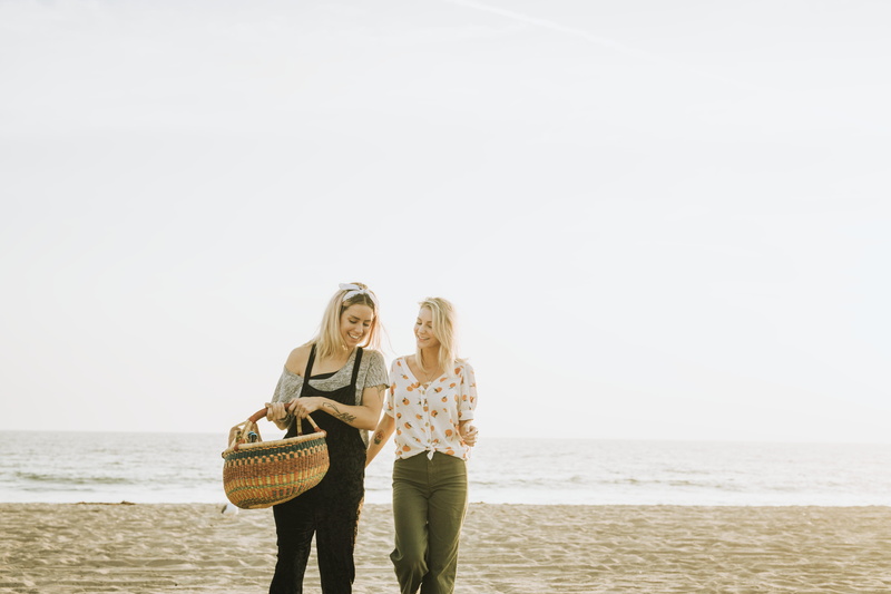 horizon over water, oceanshore, walking, standing, tattooed, smile, casual clothing, beach, three quarter length, carrying, headband, two people, smiling