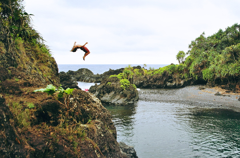 mid-air, rock, jumping, day, sky, nature, backflip, rock - object, one person, human arm, full length, formation, leisure activity, ocean, back, woman
