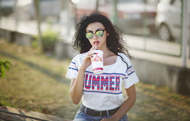 holding, women with shades, building exterior, 5K, standing, architecture, portrait, brunette, casual clothing, three quarter length, curly hair, Hit Girl