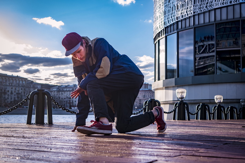 person, one person, floor, day, young adult, dancer, daytime, footbridge, side view, pier, urban, lifestyles, kneeling, youth, building exterior, dock