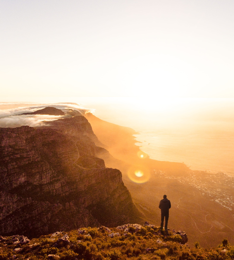 looking at view, sunset, standing, rock, men, cliff, tranquility, non-urban scene, person, rear view, haze, one person, valley, landscape, full length
