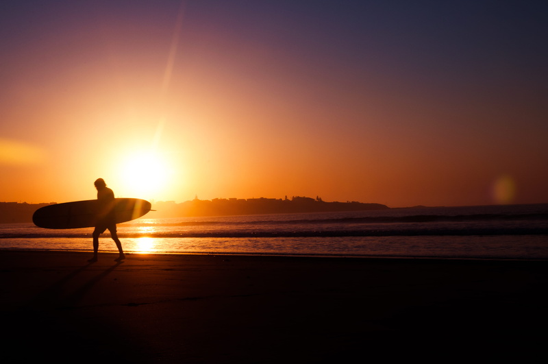 outdoors, one person, water, sunrise, lifestyles, surfing, holding, relaxation, beach, orange color, dark, land, ocean, holiday, tranquility, seashore