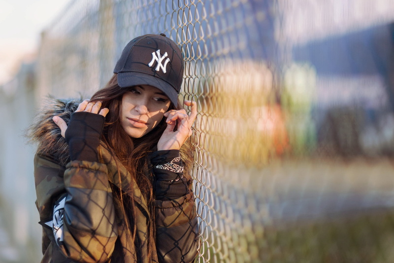 depth of field, brunette, smiling, baseball cap, day, fence, long hair, young adult, young women, hairstyle, brown hair, model, beautiful woman, looking at camera